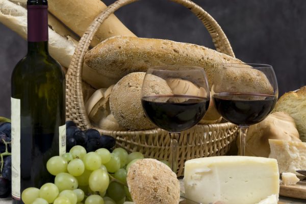 An assortment of breads, cheeses and two glasses on wine